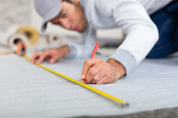 man using measuring installing new wooden laminate flooring at home