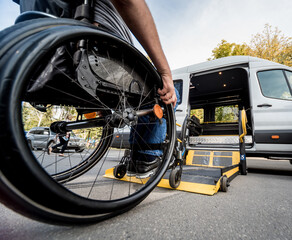 A man in a wheelchair moves to the lift of a specialized vehicle 