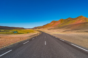 Paved Ring road going through volcanically active zone in Highlands of Iceland, resembling Martian red planet landscape, at summer and blue sky