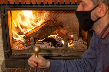 Man in protective mask stares into burning fireplace