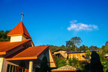 Obraz premium A high angle shot of the roof of a historic Christian church with Hill tribe village on blue sky background.
