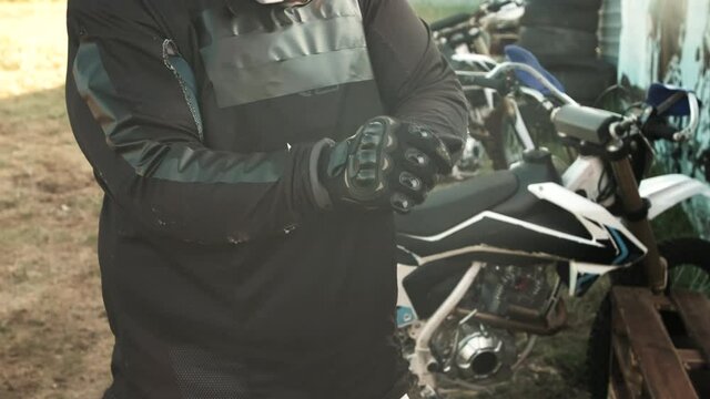 Handheld mid-section of unrecognizable man putting gloves on outdoors before riding motorcycle