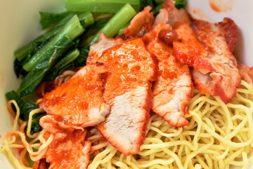 Chinese yellow egg noodles topping slice barbecue pork and boiled cabbage dressing sweet red gravy sauce on bowl