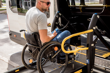 A man in a wheelchair on a lift of a vehicle for people with disabilities