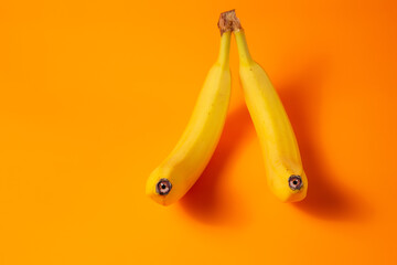 Two bananas with eyes sleep embracing. Orange background