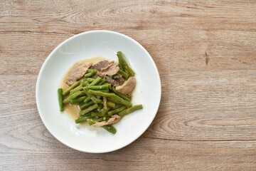 stir fried slice yard long bean with pork on soy sauce on plate