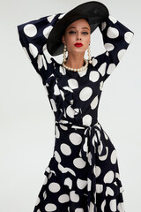 Woman with black hat wide and polka dot dress posing for fashion on a white background vertical photos - 396099569