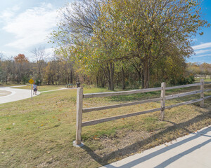 Naklejka na ściany i meble Back view people walking on curved concrete walkway at midday in nature park in Texas, America