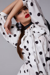 Woman with black hat wide white trousers and polka dot free shirt posing for fashion on a white and black background - 396099786