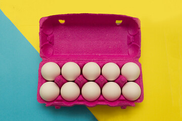chicken eggs in a pink box for eggs on a yellow background. buying eggs before Easter.