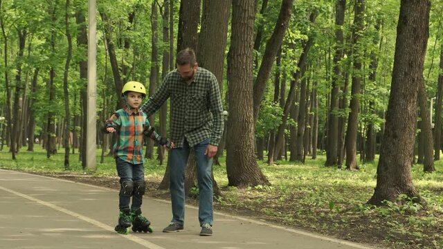 Father and son learn to roller skate in the fresh air. Father's Day.