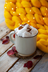 Delicious drink for cold autumn days: hot chocolate or latte with whipped cream and cinnamon. Cozy calm home atmosphere of lazy weekend morning. Yellow plaid and wooden table on background.