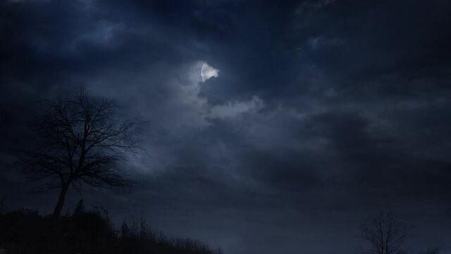 Overcast clouds blotting out moonlight. Full moon radiating white light in dark and cloudy night sky