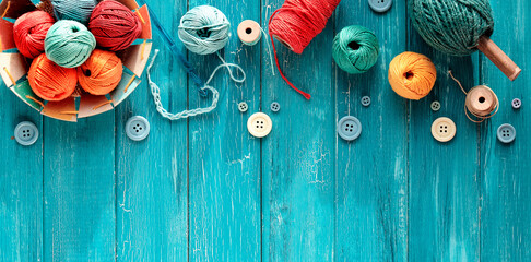 Decorative border made of wool bundles, yarn balls, buttons and cord. Latch and knitting needles....