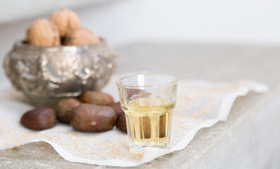 Walnuts, chestnuts and a golden liquor glass on a concrete surface