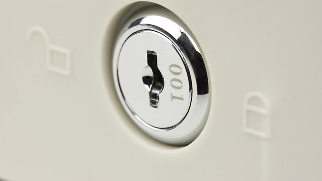 man turns the key in the lock several times, opens and closes lock, close-up view on larva of lock of safe or cash drawer