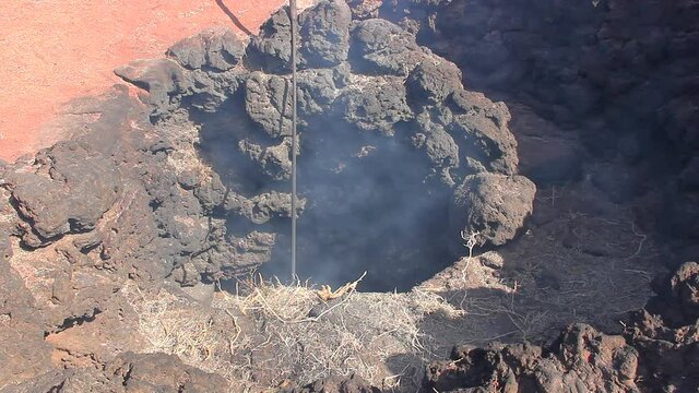 Smoke coming out of volcanic crater at Timanfaya National Park. Straw burning demonstration at Lanzarote tourist attraction. Geothermal energy, earth heat concepts