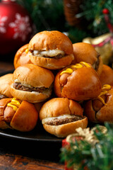 Christmas mini hamburgers, burger and hot dogs with decoration, gifts, green tree branch on wooden rustic table