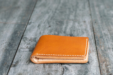 Tan brown leather bifold wallet on wood background