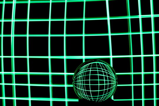Long exposure photograph of neon green colour in an abstract swirl, parallel lines pattern against a black background with reflections in a glass crystal ball. Light painting photography.