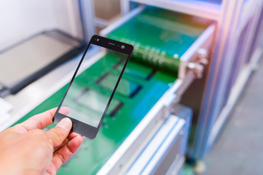 hand with robotic screen protector film or glass cover in manufacture phone factory