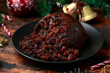 Christmas pudding with decoration, gifts, green tree branch on wooden rustic table