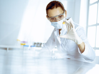 Fototapeta premium Female laboratory assistant analyzing a blood sample at hospital. Medicine, health care and researching concept