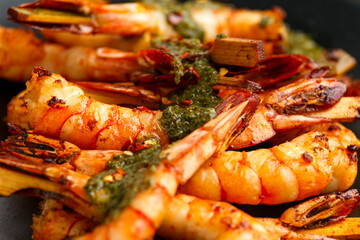 Grilled Tiger prawns skewers with garlic coriander and chili served on black plate