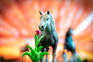 plastic figurine of a white wild horse sniffing a flower