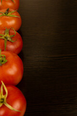 Red tomatoes with green tails lie on a dark textured wooden background, with green parsley on the other side. Eco-friendly tomatoes. Fresh tomatoes. Parsley. Tomatoes with water drops. Fresh vegetable