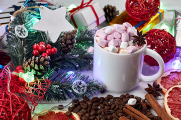Winter hot drink, gift boxes, Christmas decorations and garland. Mug of hot coffee with marshmallows, anise, cinnamon and a slice of dried grapefruit. Christmas and New Year concept.