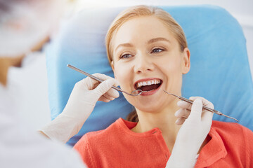 Smiling caucasian woman is being examined by dentist at sunny dental clinic. Healthy teeth and medicine, stomatology concept