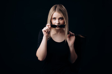 Fototapeta premium Front view of charming young woman wearing sunglasses, standing over black background and holding shopping bags. Black friday concept.
