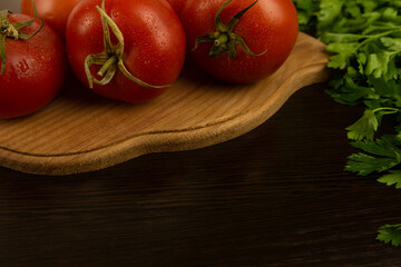 Red tomatoes on a wooden board and a dark textured wood background. With herbs.
Eco-friendly tomatoes. Fresh tomatoes. Tomatoes with water drops