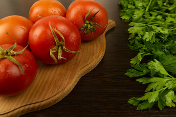 Red tomatoes on a wooden board and a dark textured wood background. With herbs.
Eco-friendly tomatoes. Fresh tomatoes. Tomatoes with water drops