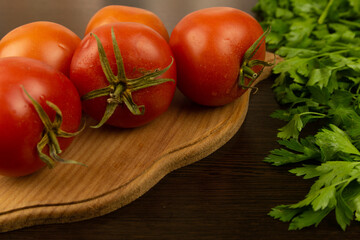 Red tomatoes on a wooden board and a dark textured wood background. With herbs.
Eco-friendly tomatoes. Fresh tomatoes. Tomatoes with water drops
