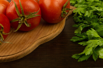 Red tomatoes on a wooden board and a dark textured wood background. With herbs.
Eco-friendly tomatoes. Fresh tomatoes. Tomatoes with water drops