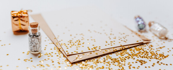 Blank note with envelope, gifts and gold glitter stars on white background