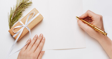 Girl writing blank note with spruce branch and gold pen on white background