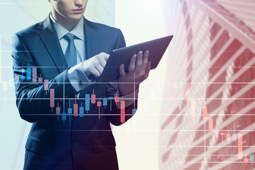Double exposure of businessman using the tablet with cityscape and financial graph