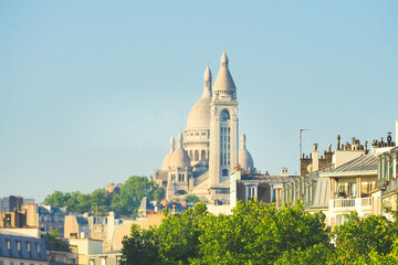 Obraz premium Montmartre on the blue sky background among residential modern areas. Basilica of Sacre Coeur or Basilica of the Sacred Heart, Paris, France