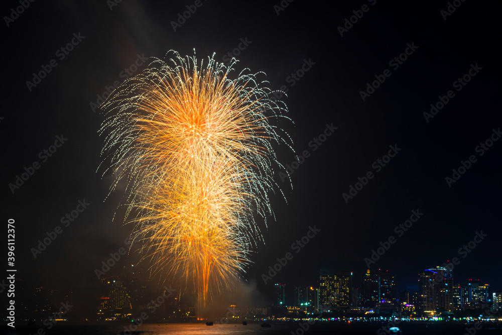 Wall mural firework festival with beach foreground and city background at pattaya beach, thailand. colorful fir