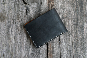 Black leather bifold money and card wallet on wood