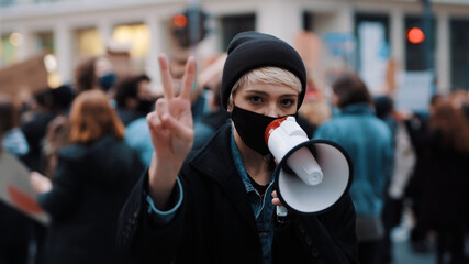 Woman with face mask and megaphone supporting anti-racism protests. Peace gesture. High quality photo