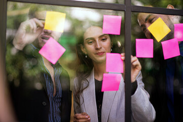 Business people meeting in office, analysis, computational, reasoning, brainstorming, finding business development opportunities, use post it notes to share idea, Sticky note on glass wall.