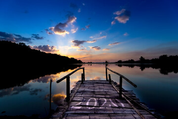Naklejka na ściany i meble Bamboo bridge numbers 2020 By the lake On the background of the sunset sky