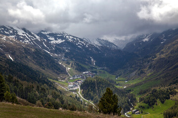 Fototapeta premium A village in the Alps among forests, against the backdrop of mountain peaks.