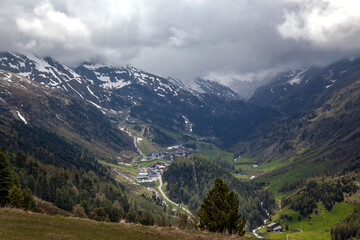 A village in the Alps among forests, against the backdrop of mountain peaks.