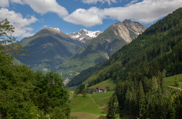 A village in the Alps among forests, against the backdrop of mountain peaks.