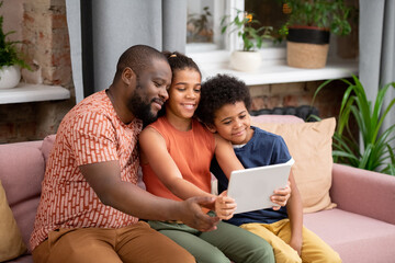 Happy family of father, son and daughter with digital tablet watching movie